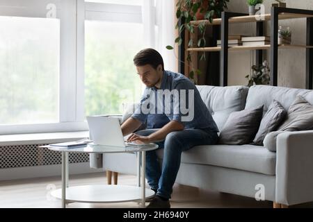 Concentrated young businessman working on computer at home. Stock Photo
