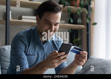 Happy young man shopping using mobile application. Stock Photo