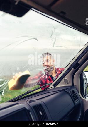 Man cleaning motorhome glass outdoor Stock Photo