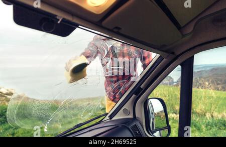 Man cleaning camper van windshield outdoor Stock Photo