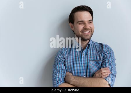 Smiling young man looking in distance posing on white studio background. Stock Photo