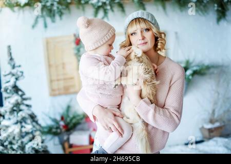 Mom and daughter close - up on the background of a snow-covered Christmas tree and wooden shutters. Stock Photo