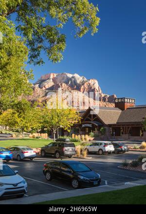 Springdale, Utah, USA. View across car park in front of the Switchback Restaurant to the towering red sandstone cliffs of Zion National Park, autumn.