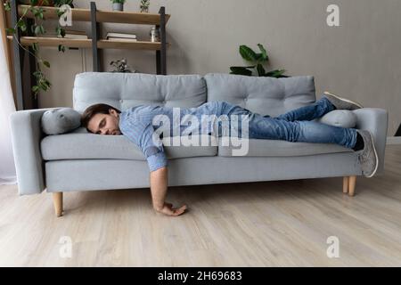 Exhausted young man fell asleep on comfortable couch. Stock Photo