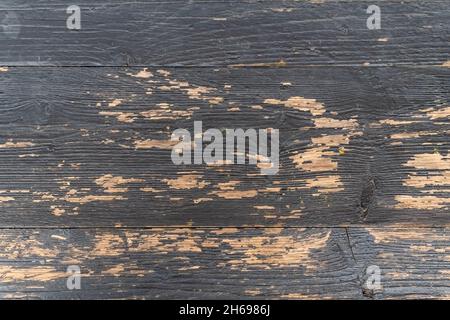 Black paint peeled off on old wood planks revealing the light color of the wood. Reference material for artists. Stock Photo