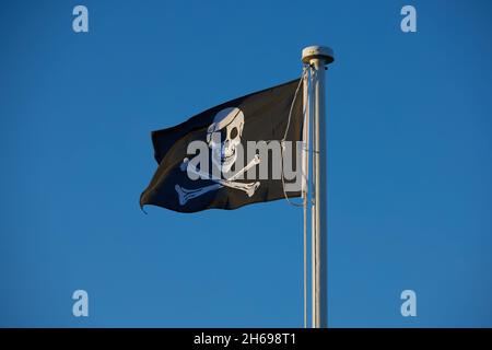 Black flag depicting skull and two crossing bones seen flying outdoors. Stock Photo