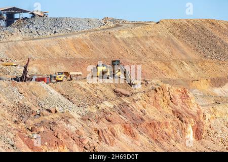 Mining trucks and machinery in Corta Atalaya open mine pit. Deep excavation of pyrite and extraction of minerals of cooper and gold in municipality of