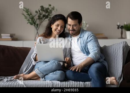 Happy young couple using laptop, relaxing on couch together Stock Photo