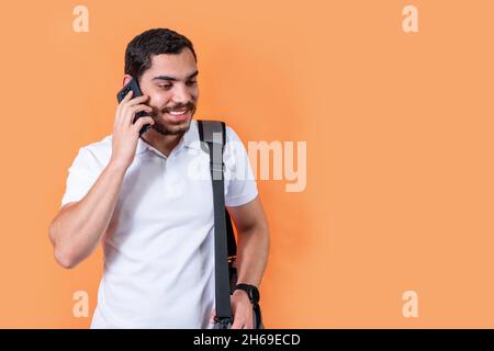 Happy bearded student with a handbag on his shoulder is talking on the phone Stock Photo