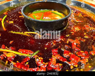 Red hot spicy chilli peppers swimming in world famous Sichuan Hotpot Stock Photo