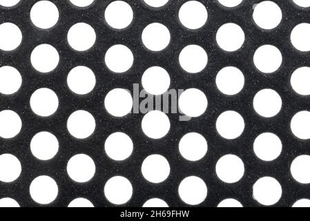Macro shot of a black metal surface with round holes and white dots, isolated on a white background. Stock Photo