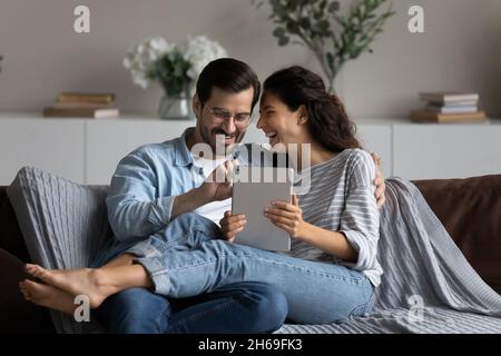 Happy laughing couple having fun with tablet at home together Stock Photo