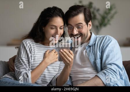 Head shot excited couple looking at smartphone screen, reading news Stock Photo