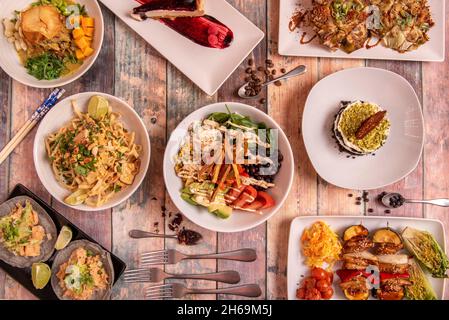 Top view image of vegan food dishes, boletus croquettes, poke bowl with wakame seaweed salad, edamame and pumpkin cubes, artichoke flowers, tacos with Stock Photo