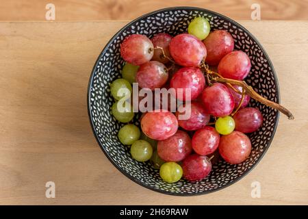 Bowl of red and white seedless grapes viewed from the top on wooden table Stock Photo