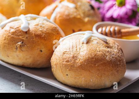 Traditional Easter cross buns with raisins on a gray plate, close-up. Stock Photo