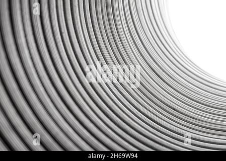 Flexible corrugated aluminum tube seen from the inside, resistant to high temperatures, isolated on a white background, selective focus. Stock Photo