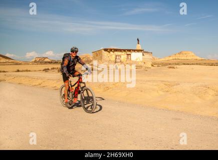 Man cycling in the Bardenas Reales a Spanish UNESCO semi arid natural desert park with a lunar landscape in the Navarra region of Northern Spain Stock Photo