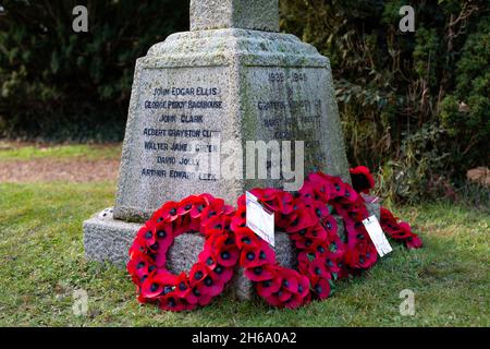 Red poppy wreaths laid on a war memorial in remembrance of war dead, Suffolk UK Stock Photo