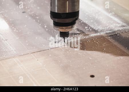 End mill processes transparent plastic sheet on a CNC milling machine, close-up photo with selective soft focus Stock Photo