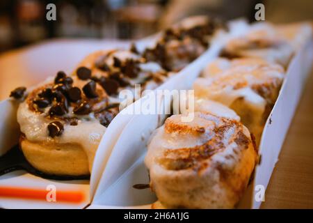 A closeup of fresh cinnamon rolls with chocolate on the table in a cafe Stock Photo