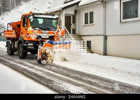 Goslar, Germany, January 26, 2021: Orange colored snow plow with clearing shovel clears snow on the road in winter Stock Photo