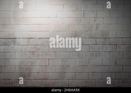 White block wall aged by humidity and illuminated with overhead light. Background. Stock Photo