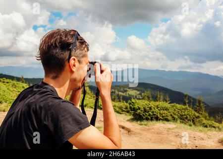 Photographer taking pictures of Carpathian mountains landscape on top of Hoverla. Man using camera to make photos and footage. Traveling wtih digital Stock Photo