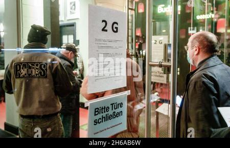 Hamburg, Germany. 14th Nov, 2021. Visitors to a performance at the Hamburger Kammerspiele pass a notice at the entrance pointing out the 2G rules now in force at the theatre. As of November 14, 2021, the Altonaer Theater and the Harburger Theater will also switch to 2G operation with reduced seating capacity Credit: Markus Scholz/dpa/Alamy Live News Stock Photo