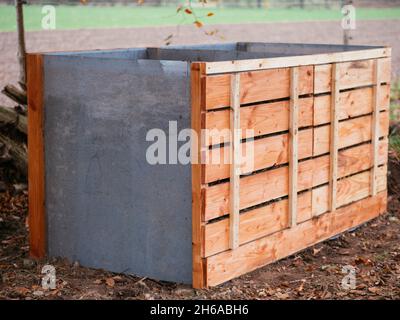 Home made compost bin with two chambers made from Douglas fir timber and perforated metal sheets. Stock Photo