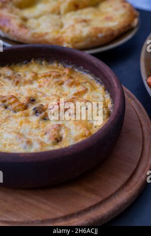 baked suluguni cheese with tomatoes of national Georgian cuisine in earthenware on ketsi Stock Photo