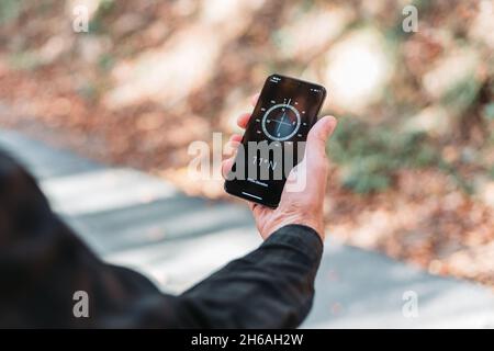 Man hand holding a phone with a compass map on it. Outdoors activity Stock Photo