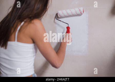 Happy young attractive woman painting wall in apartment Stock Photo