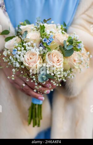 Winter bridal bouquet in hands. Beige roses, blue and gray flowers. Blue  dress and beige fur coat on the bride. Wedding bouquet in pastel colors  close-up. Flowers Stock Photo - Alamy