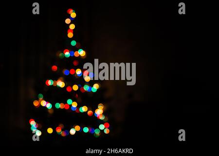 Christmas tree multicolored bokeh on dark background. Defocused multi colored lights. New Year, Christmas background, abstract texture. Copy space Stock Photo