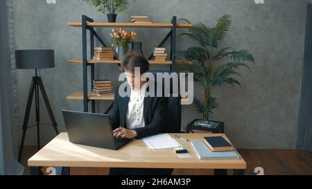 Young perspective businessman is actively working while sitting at the table in the office.Young attractive businessman working on a laptop in his Stock Photo