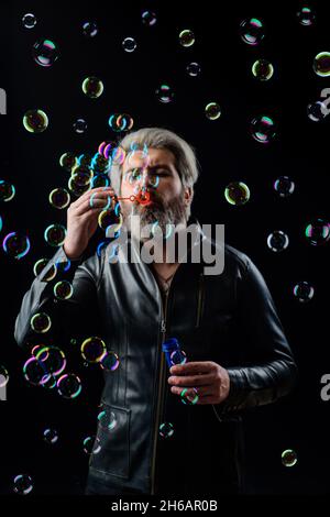 Bearded man blowing Soap bubbles. Play with inflate bubbles. Happiness. Good mood. Childhood. Stock Photo