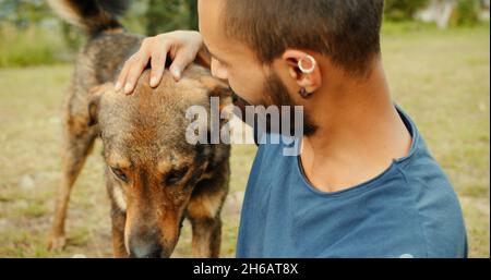 A young Indian guy petting a stray dog in a park Stock Photo