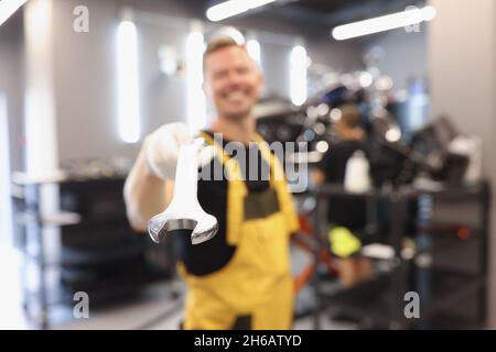 Uniformed car repairman holds wrench in car repair shop Stock Photo