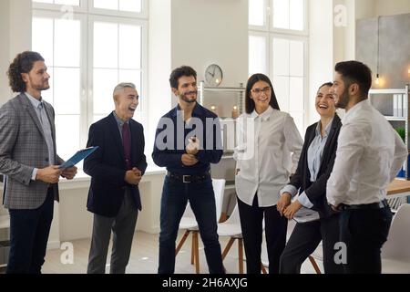 Happy young business team having a fun conversation with a mature manager in the office. Stock Photo