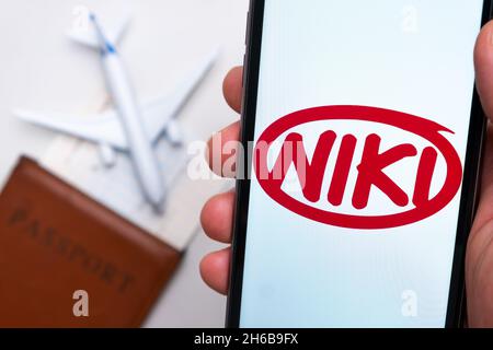 Niki Airlines app on the cell phone screen in mans hand with plane, boarding pass and passport on the background. The concept of the airlines mobile application. November 2021, San Francisco, USA Stock Photo
