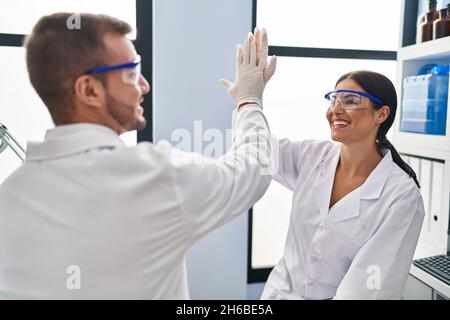 Man and woman scientist partners high five with hands raised up at laboratory Stock Photo