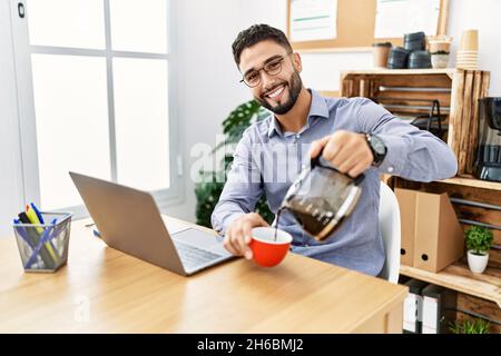 Young arab man smiling confident drinking coffee working at office Stock Photo