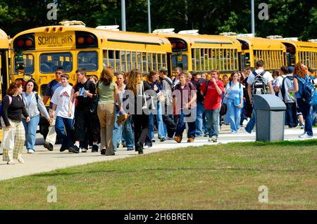High school students leave at the end of the day to ride school busses for transportation home Stock Photo