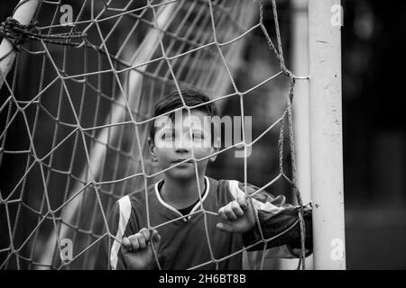 A teen boy portrait near the gate on the football field. Black and white photo. Stock Photo