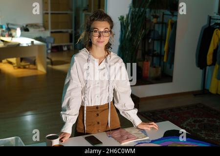 Young self-employed tailor woman in studio. Designer work with textile, fashion clothes collection Stock Photo