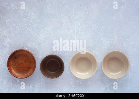four small round empty bowls in a row on grey concrete background, top view, copy space Stock Photo