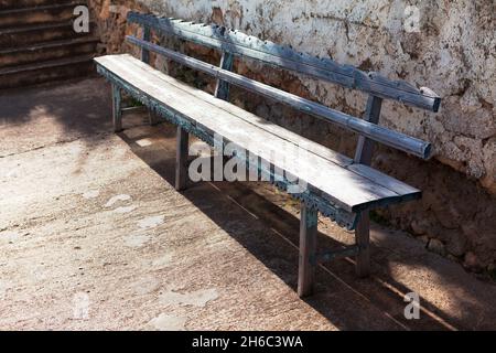 Old wooden bench near wall . Quiet place for seating Stock Photo