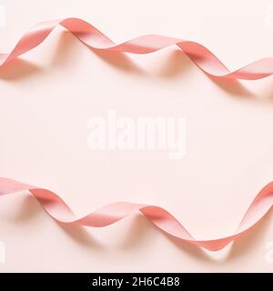 Curly pink ribbon tape on pink background. top view, copy space Stock Photo