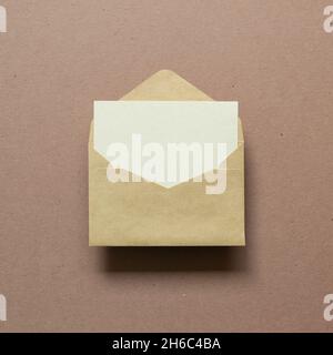 Blank card in kraft envelope on brown background. top view, copy space Stock Photo